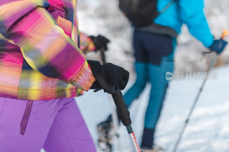 特写的徒步旅行者抱着一个徒步杆/工作人员，而徒步旅行在雪地里